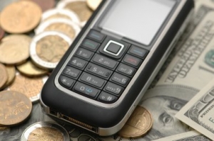 Mobile phone with coins and dollar bank notes