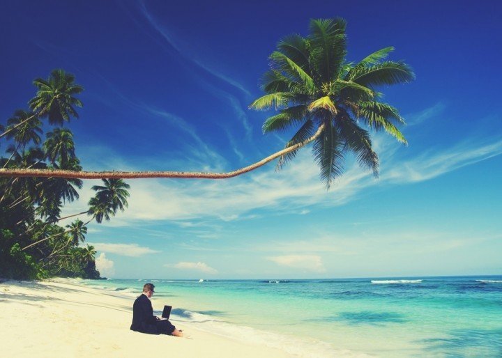 Businessman working with his laptop on the summer beach