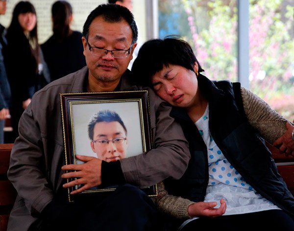 Wei Zexi's parents holding a framed photo of their son, who died of a rare form of cancer after receiving ineffective treatment at a Beijing hospital. Photo credit: Global Times on Twitter.