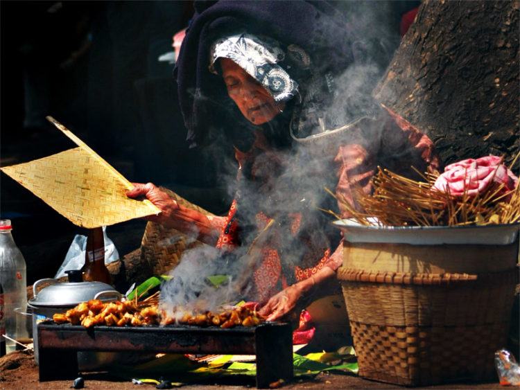 A woman preparing grilled chicken skewers, a dish known in Indonesia as Sate. Photo credit:Adhi Rachdian.