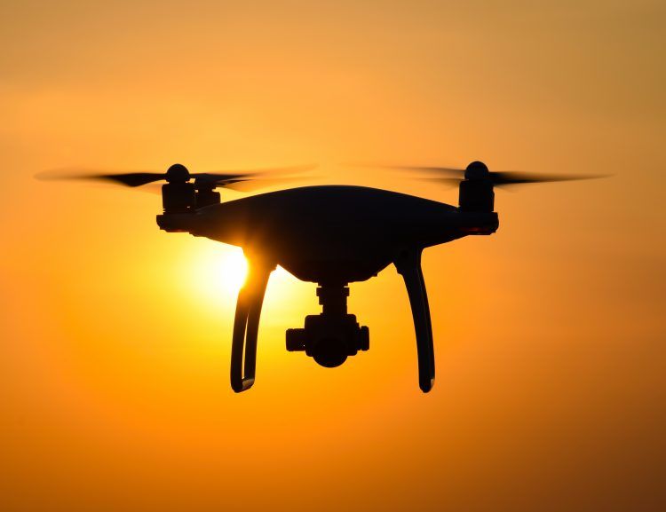 Quadrocopters silhouette against the background of the sunset. Flying drones in the evening sky.
